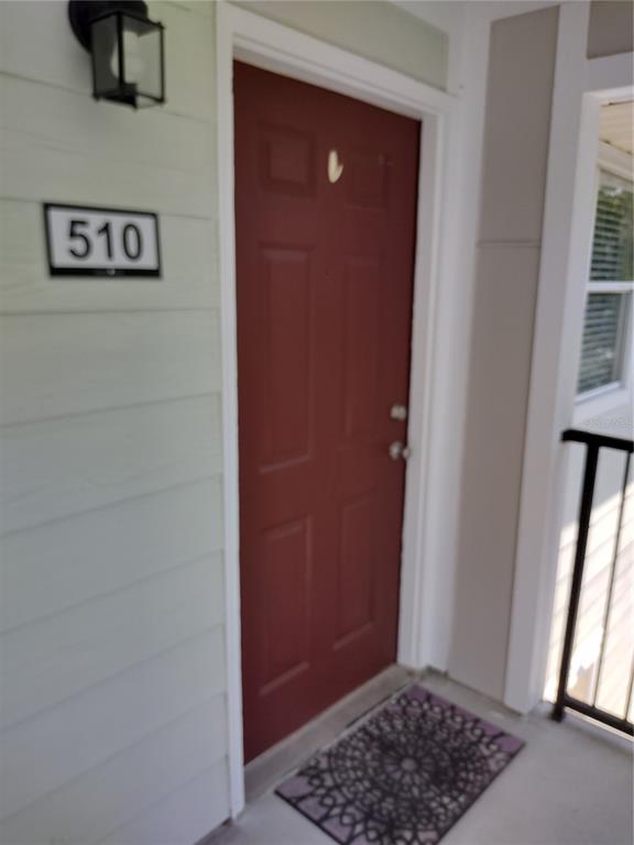 A red front door with a house number sign and a porch light on the exterior — 2360 SW ARCHER ROAD UNIT 510, GAINESVILLE, FL