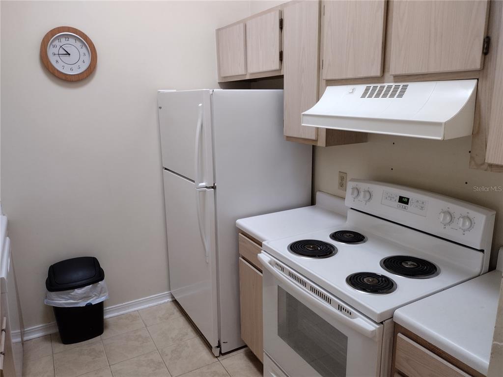 A kitchen features white appliances, light wood cabinets, and a wall-mounted clock — 2360 SW ARCHER ROAD UNIT 510, GAINESVILLE, FL