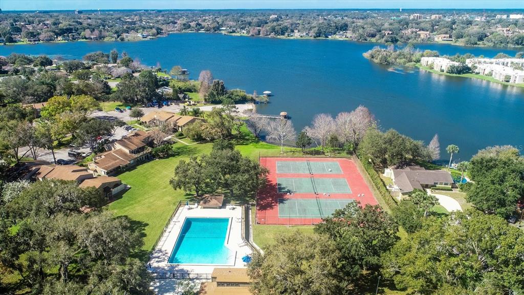An aerial view shows a swimming pool and tennis courts next to a lake — 671 POST OAK CIRCLE UNIT 107, ALTAMONTE SPRINGS, FL