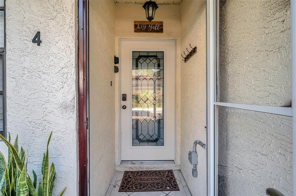 A front entryway features a white door with a glass insert, a welcome mat, and stucco walls — 6421 DREXEL DRIVE UNIT 4, PORT RICHEY, FL