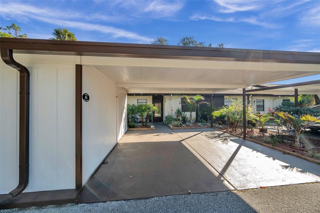 A covered carport leads to the entrance of a single-story home with white siding — 6421 DREXEL DRIVE UNIT 4, PORT RICHEY, FL