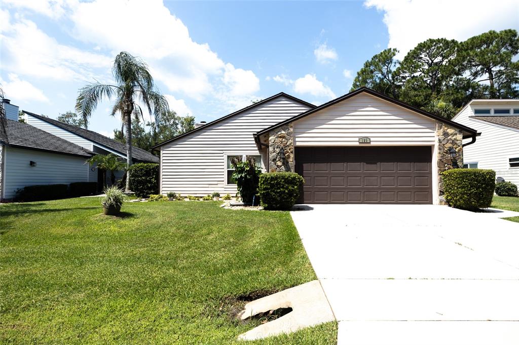 A single-story house with light siding, a stone-accented garage, and a palm tree in front — 120 GULL CIRCLE N, DAYTONA BEACH, FL