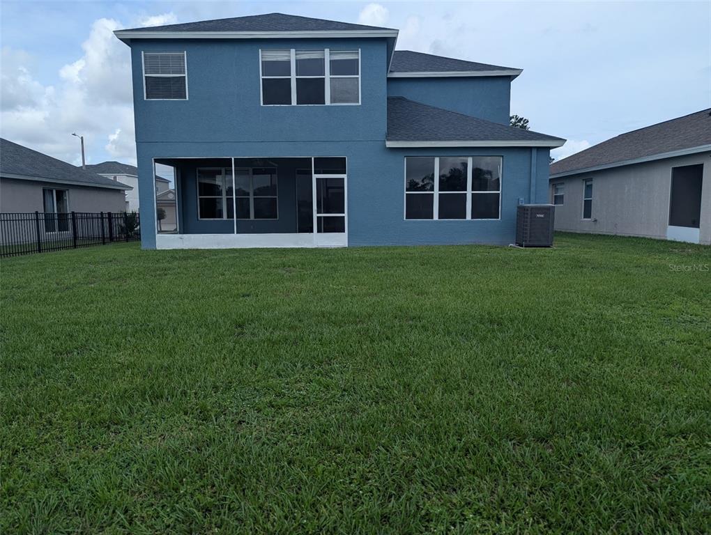 The rear exterior of a two-story blue house features a screened-in patio and lawn — 13308 AMBER SKY PLACE, RIVERVIEW, FL