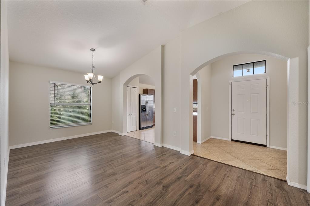 A dining area with wood-look flooring features an arched entryway leading to a tiled foyer — 7019 HEATHERBROOK DRIVE, LAKELAND, FL