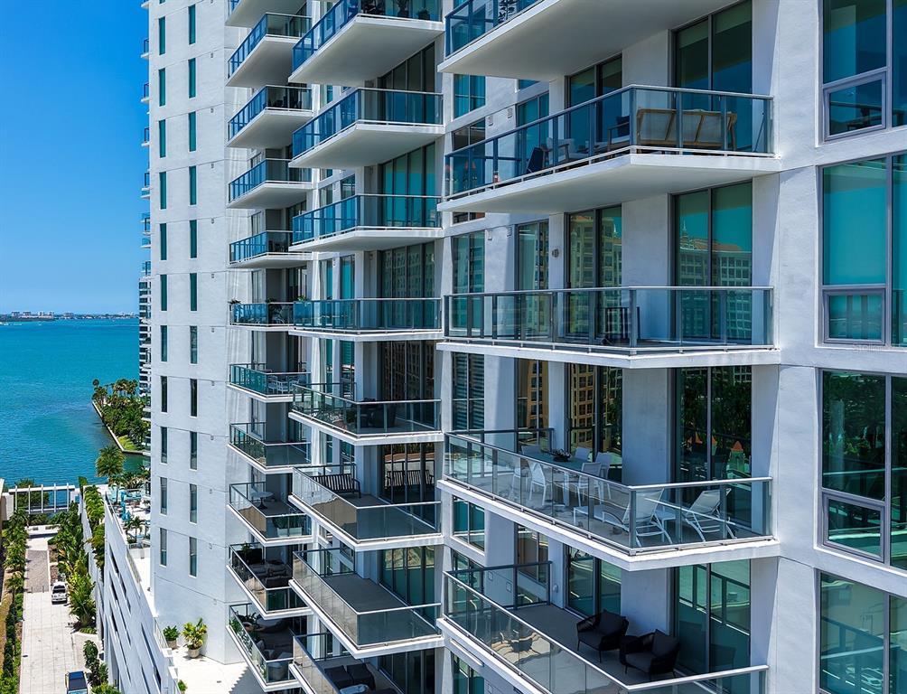 An exterior view of a high-rise building featuring stacked balconies overlooking a body of water — 301 QUAY COMMONS UNIT 1007, SARASOTA, FL