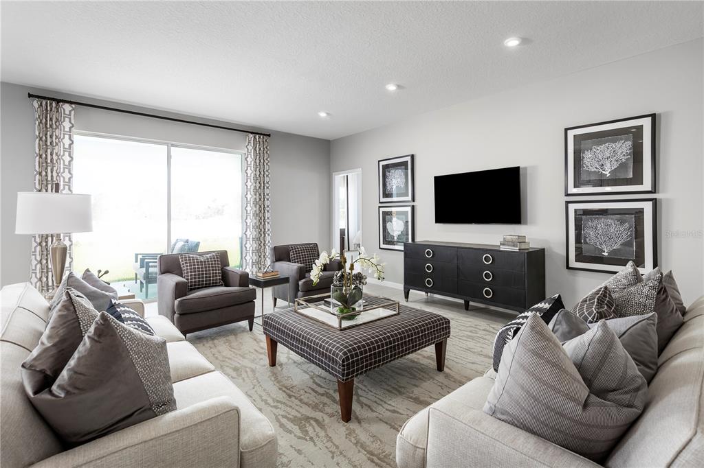A living room features light-colored sofas, a plaid ottoman, two armchairs, and a wall-mounted television — 8466 SWAN VIEW CIRCLE, LEESBURG, FL