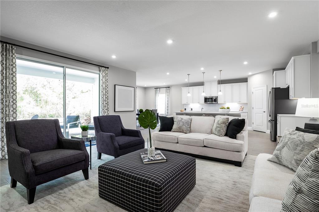 A living room with a sofa, two armchairs, and a large checkered ottoman near a kitchen — 8466 SWAN VIEW CIRCLE, LEESBURG, FL