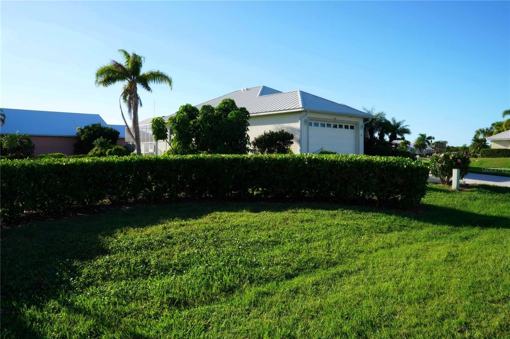 A single-story house with a metal roof and a garage behind a manicured hedge — 2 WINDWARD PLACE, PLACIDA, FL