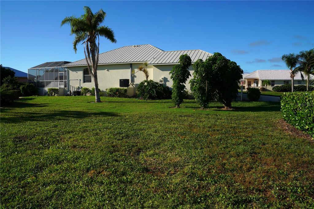 A single-story house with a metal roof and a screened-in patio sits on a lawn — 2 WINDWARD PLACE, PLACIDA, FL