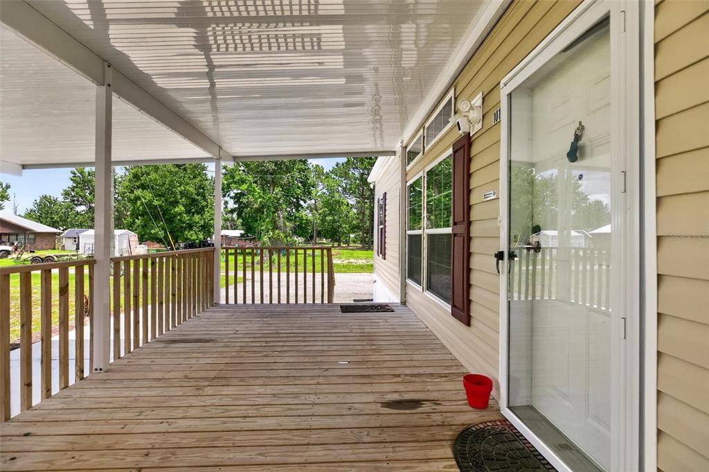 A covered wooden porch with railings leads to the front door of a mobile home — 101 TROUT TRAIL, CRESCENT CITY, FL