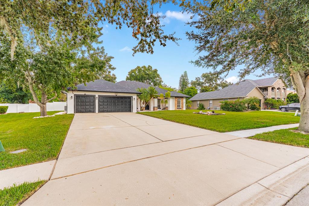 A single-story house with a two-car garage and a concrete driveway sits on a lawn — 1670 TAYLOR RIDGE LOOP, KISSIMMEE, FL