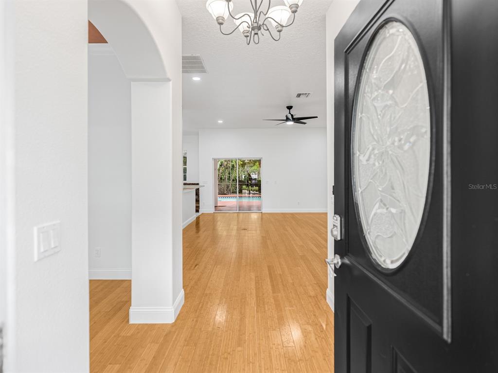 The view from an open front door reveals a bright foyer with hardwood flooring — 1670 TAYLOR RIDGE LOOP, KISSIMMEE, FL