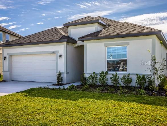 A single-story house with a white stucco exterior, a two-car garage, and a front lawn — 6428 QUARTET STREET, MASCOTTE, FL