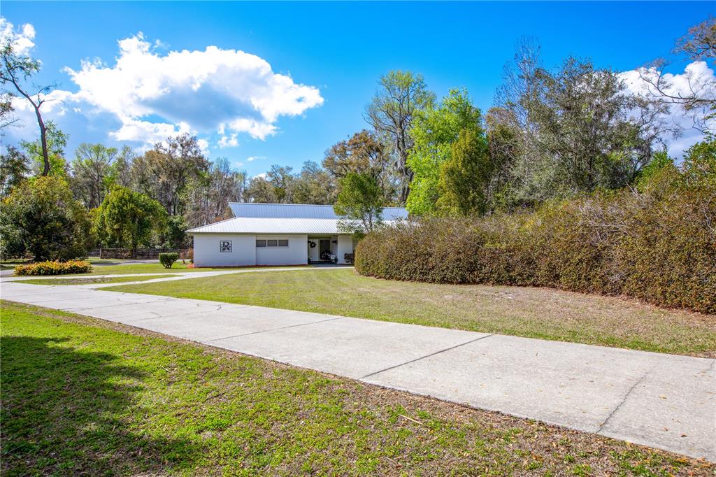 A white single-story house with a metal roof sits at the end of a driveway — 12182 SW STATE ROAD 45, ARCHER, FL