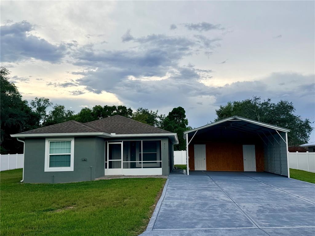 A single-story gray house with a screened front porch and an attached metal carport — 511 MOUNTAIN DRIVE, BABSON PARK, FL