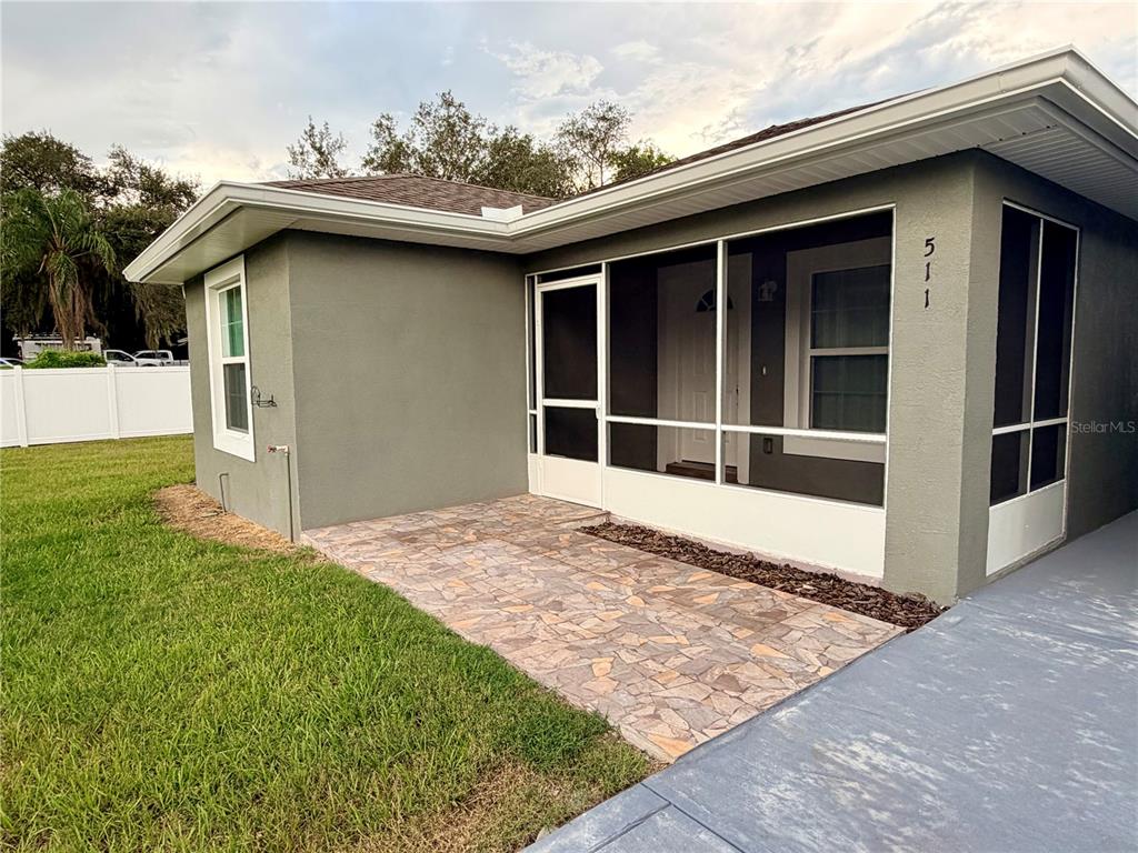 A gray house features a screened-in front porch with a stone-patterned patio floor — 511 MOUNTAIN DRIVE, BABSON PARK, FL