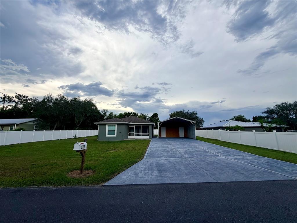 A single-story house with a carport, a large concrete driveway, and a white vinyl fence — 511 MOUNTAIN DRIVE, BABSON PARK, FL