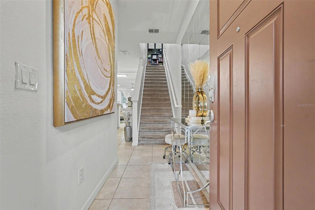 An entryway features a staircase, tiled flooring, a console table, and a large abstract painting — 5374 SYLVESTER LOOP, TAMPA, FL