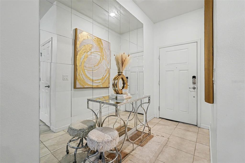 A mirrored entryway features a glass console table, two stools, and abstract wall art — 5374 SYLVESTER LOOP, TAMPA, FL