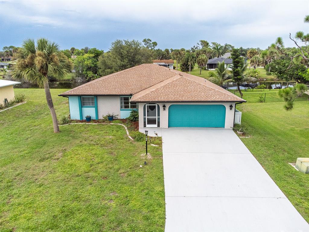 A single-story house with a teal garage door, light-colored brick siding, and a brown roof — 199 CADDY ROAD, ROTONDA WEST, FL