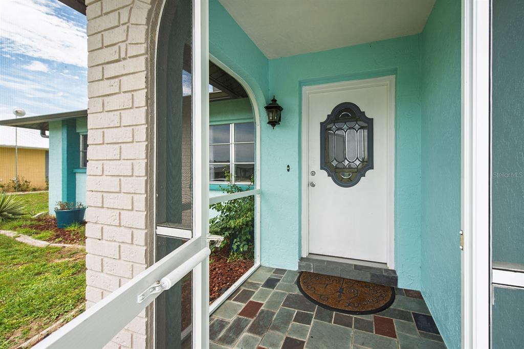 A turquoise-painted entryway features a white front door with a decorative glass insert — 199 CADDY ROAD, ROTONDA WEST, FL