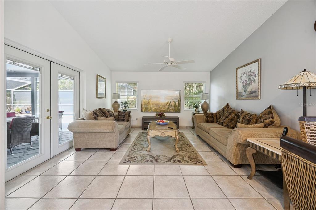 A screened-in patio features a swimming pool with steps and outdoor seating under a roof — 2948 PEMBRIDGE STREET, KISSIMMEE, FL