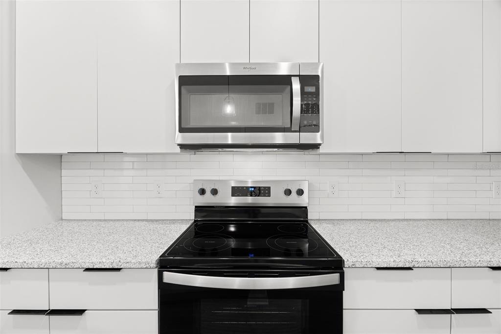 A kitchen features white cabinets, a stainless steel microwave, a black electric stove, and countertops — 1700 RANCH ROAD UNIT A2-12210, NOKOMIS, FL