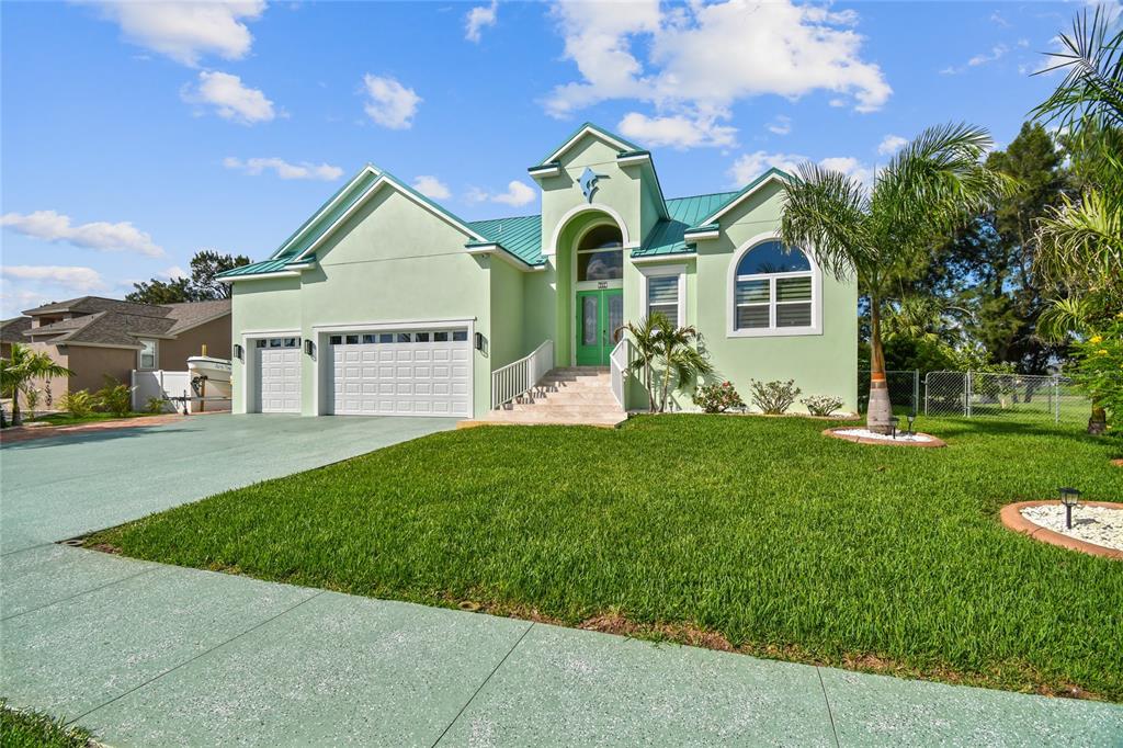 A light green house with a metal roof, a two-car garage, and a front lawn — 711 EAGLE LANE, APOLLO BEACH, FL