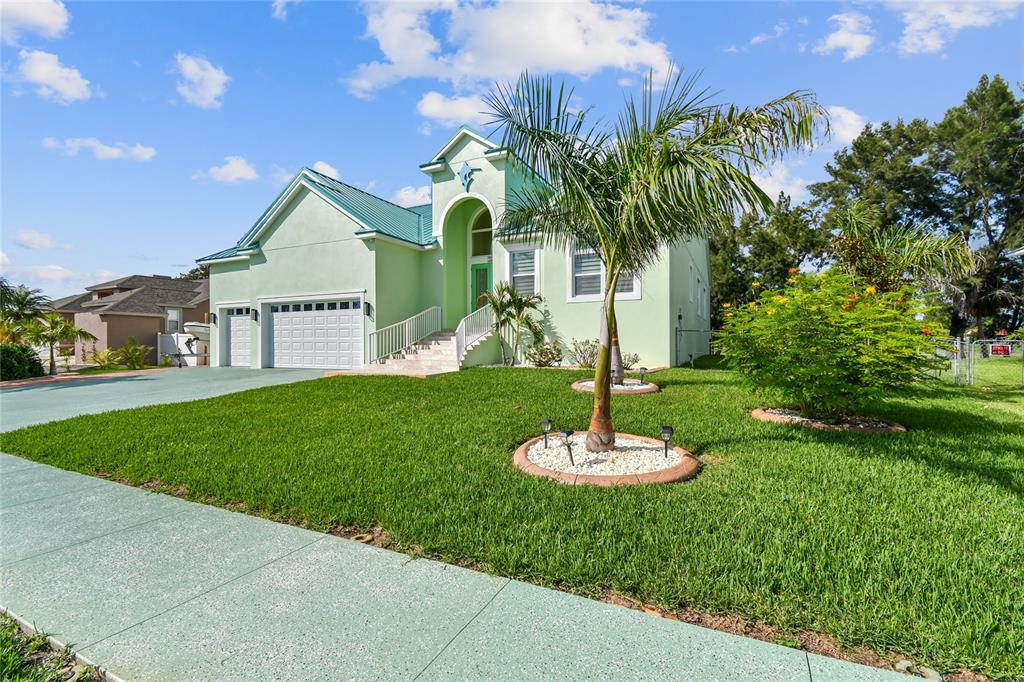 A light green house with a metal roof, two-car garage, and a palm tree — 711 EAGLE LANE, APOLLO BEACH, FL