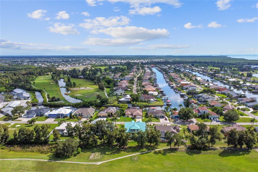 An aerial view shows residential homes along a canal with a golf course nearby — 711 EAGLE LANE, APOLLO BEACH, FL