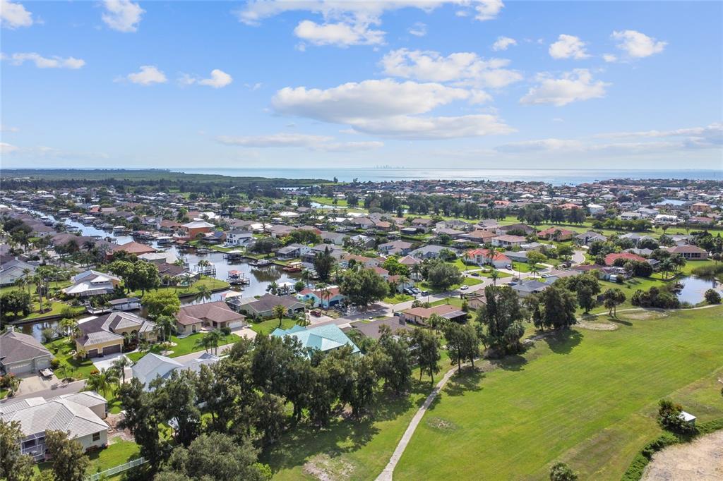 An aerial view shows a residential neighborhood with houses, canals, and a large grassy field — 711 EAGLE LANE, APOLLO BEACH, FL