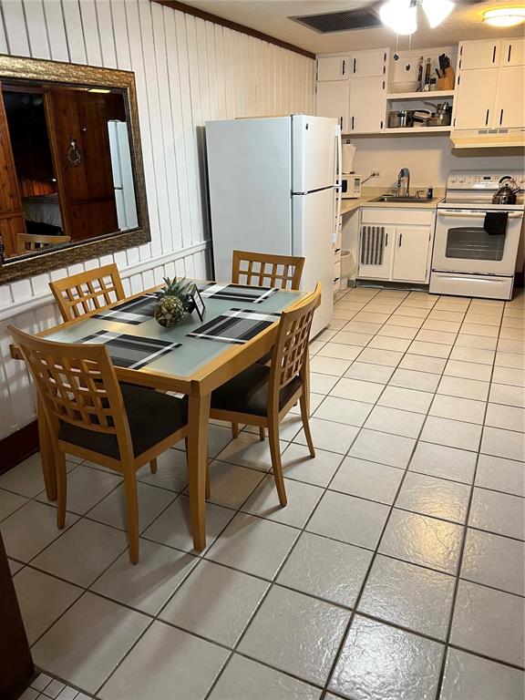 A kitchen and dining area with white cabinets, tile flooring, and a glass-topped table — 10301 US HIGHWAY 27 UNIT 100, CLERMONT, FL