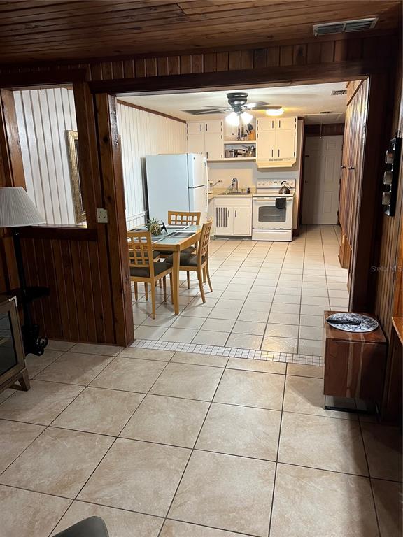 A kitchen and dining area with tile floors, wood-paneled walls, and white cabinetry — 10301 US HIGHWAY 27 UNIT 100, CLERMONT, FL