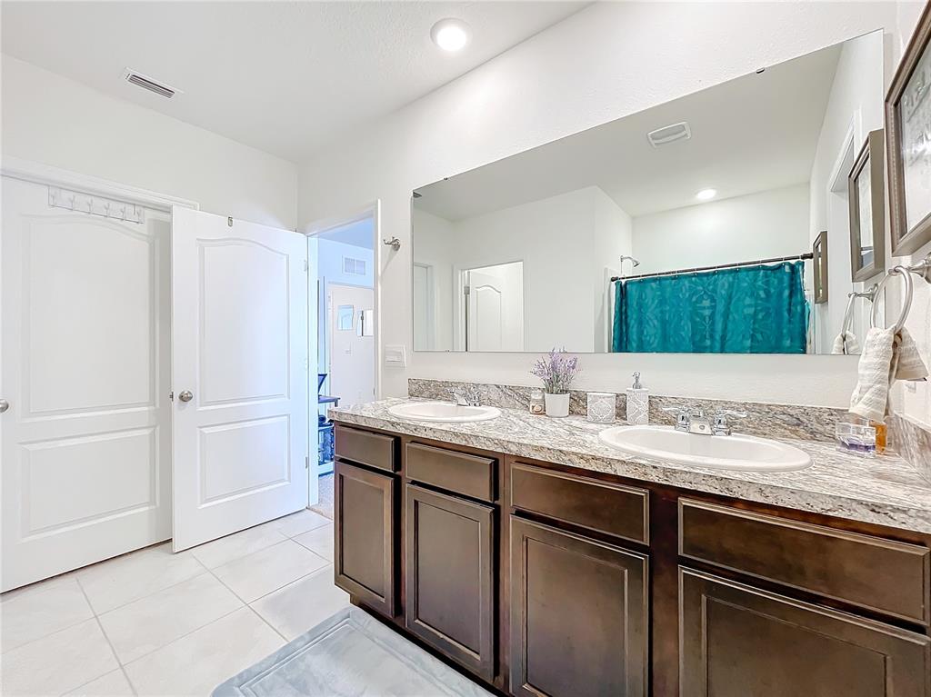 A bathroom features a double-sink vanity with dark wood cabinets and a granite countertop — 1634 REDDISH EGRET COURT, DAVENPORT, FL