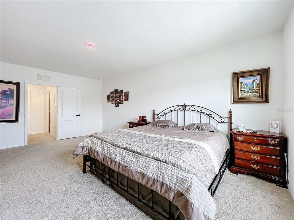 A bedroom features a metal-framed bed, a wooden dresser, and a doorway leading to another room — 1634 REDDISH EGRET COURT, DAVENPORT, FL