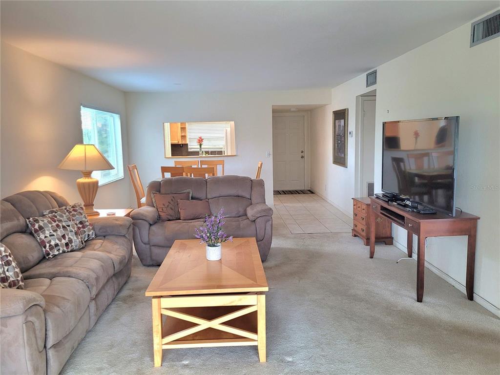 A dining area and living room feature carpeted floors, a sofa, and a wooden table — 9861 Sunrise Lakes  Blvd SUNRISE LAKES BOULEVARD UNIT 310, SUNRISE, FL