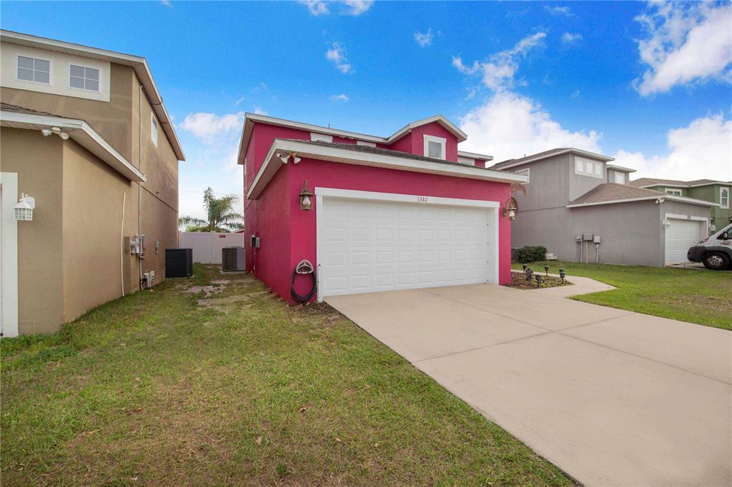 A bright pink two-story house features a white garage door and a concrete driveway — 1382 SALISBURY DRIVE, WINTER HAVEN, FL