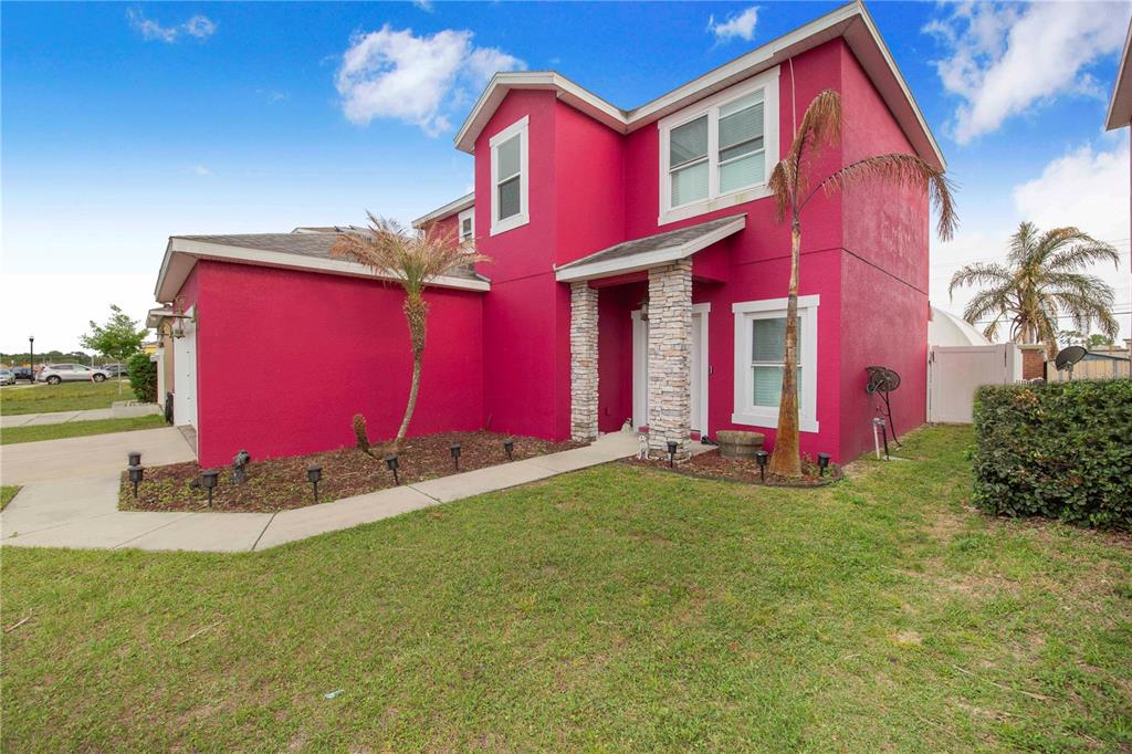 A two-story house with bright pink stucco siding and a stone-accented entryway — 1382 SALISBURY DRIVE, WINTER HAVEN, FL