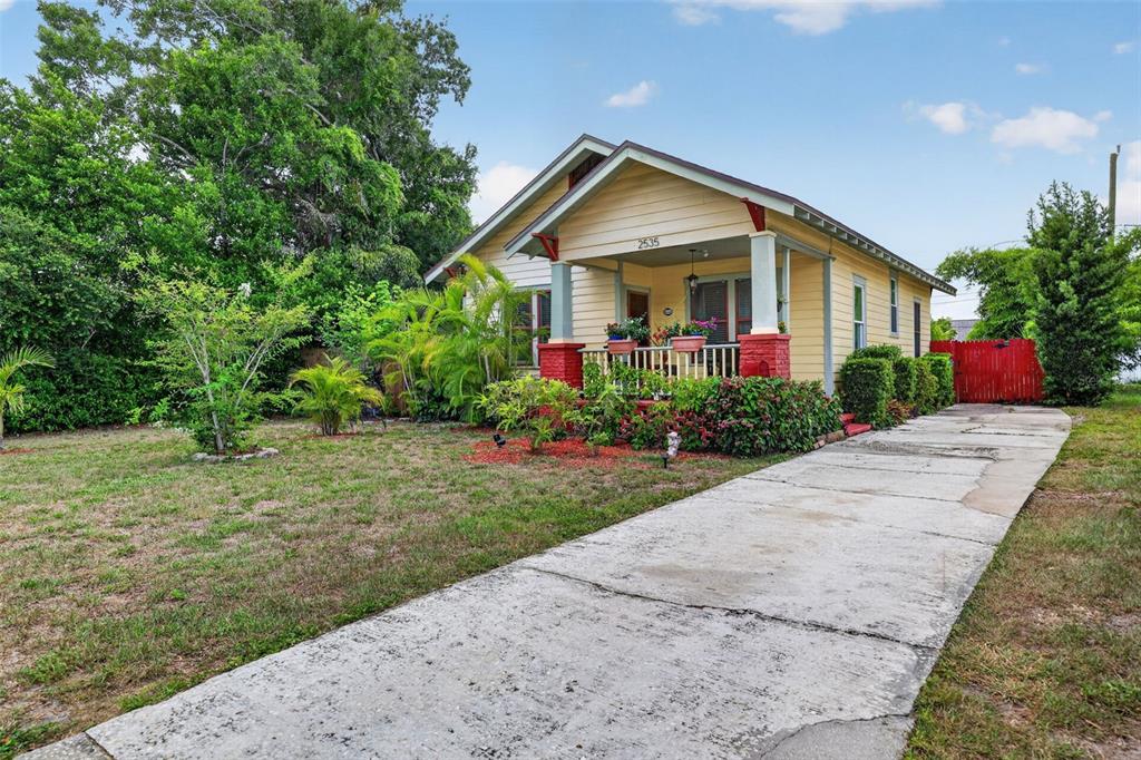 A yellow bungalow with a front porch and a concrete driveway sits on a grassy lot — 2535 15TH AVENUE N, ST PETERSBURG, FL