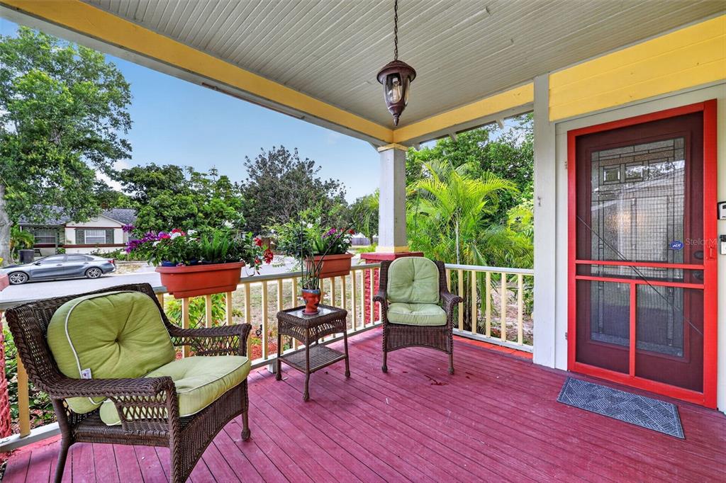 A covered porch features a red wooden floor, two wicker chairs, and a red screen door — 2535 15TH AVENUE N, ST PETERSBURG, FL