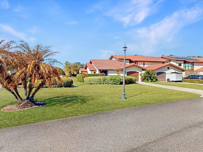 A single-story house with a red tile roof sits behind a large lawn and palm — 118 COVENTRY LANE, HAINES CITY, FL
