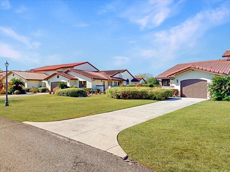 A view of two single-story houses with tile roofs and concrete driveways under a blue sky — 118 COVENTRY LANE, HAINES CITY, FL