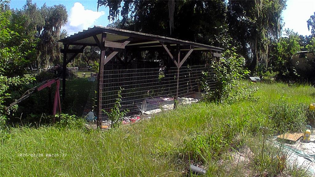 An outdoor wooden shelter with a wire fence enclosure stands in a grassy yard — 16979 SE 6TH LANE, SILVER SPRINGS, FL
