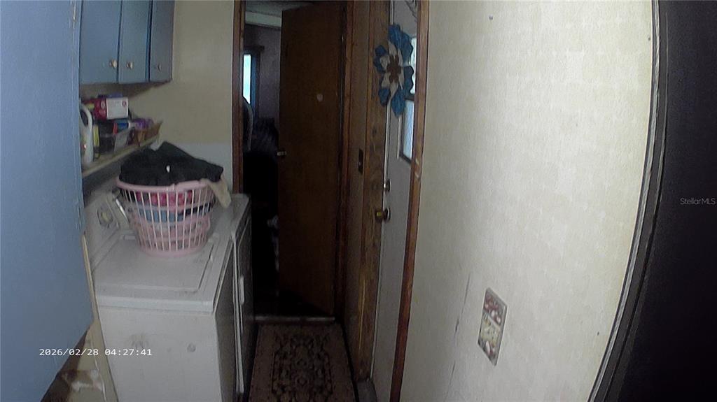 A laundry area features a white washing machine, overhead cabinets, and a doorway leading inside — 16979 SE 6TH LANE, SILVER SPRINGS, FL