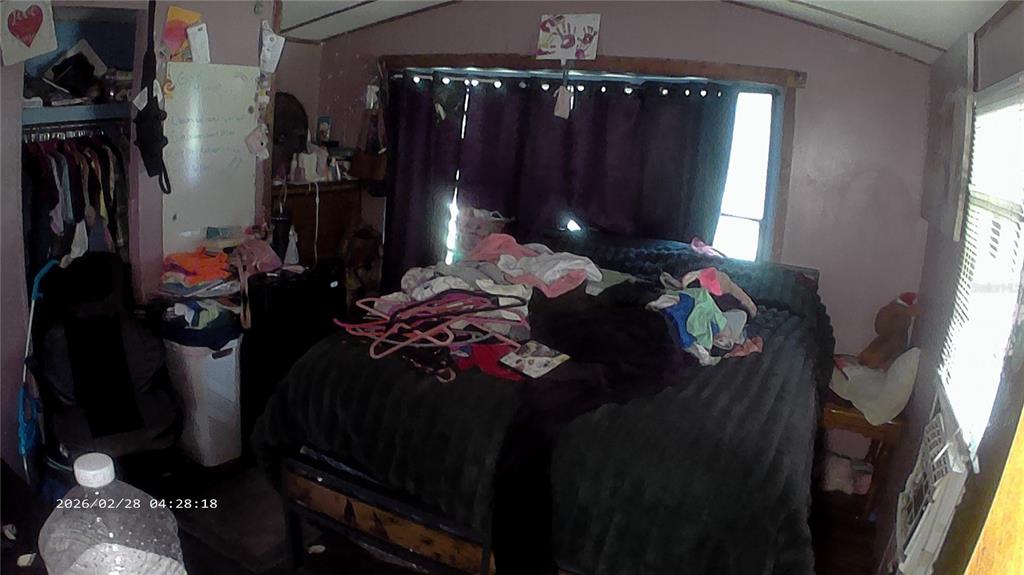 A bedroom features a bed covered in clothes, a closet, and a window with blinds — 16979 SE 6TH LANE, SILVER SPRINGS, FL