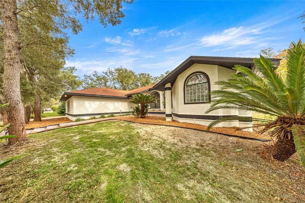 A single-story house with a stucco exterior, a brown roof, and a large arched window — 375 N HIGHVIEW AVENUE, HERNANDO, FL