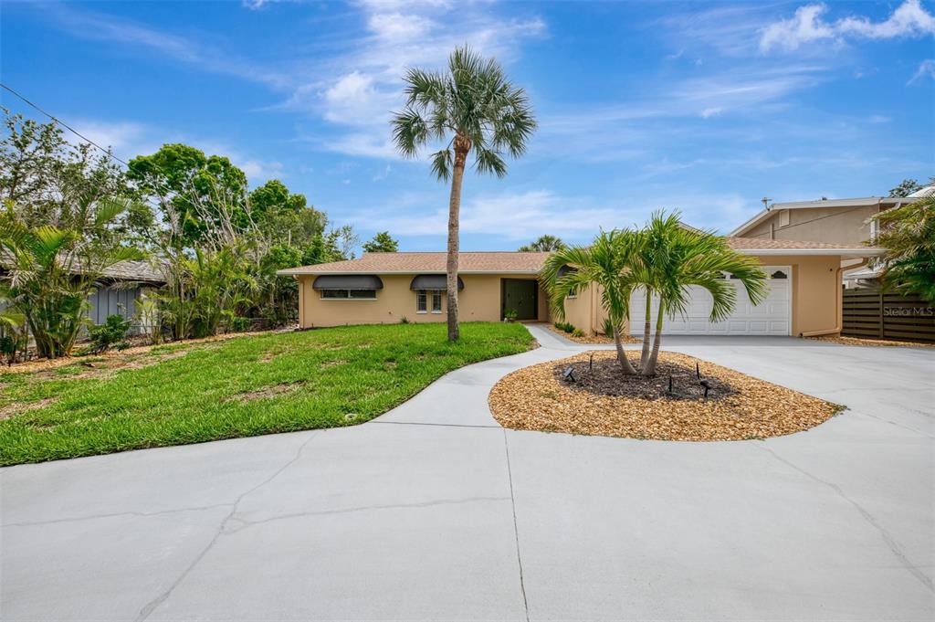 A single-story house with a tan exterior, a palm tree, and a concrete driveway — 4946 COMMONWEALTH DRIVE, SARASOTA, FL