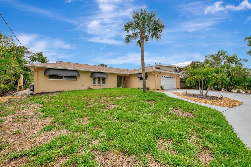 A single-story house with a tan exterior, a palm tree, and a concrete driveway — 4946 COMMONWEALTH DRIVE, SARASOTA, FL