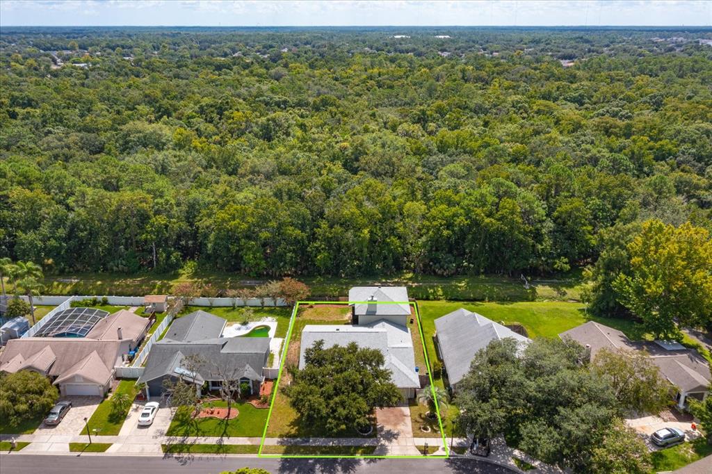 An aerial view shows a suburban house with a large tree in the front yard — 1006 BECKSTROM DRIVE, OVIEDO, FL