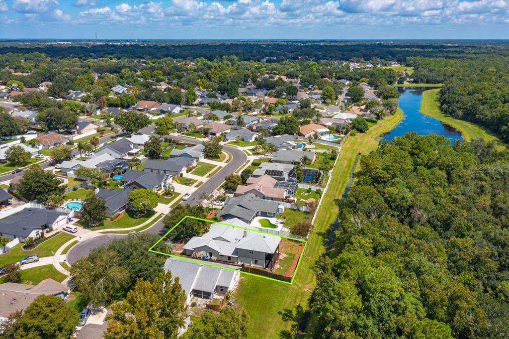 An aerial view shows a suburban house with a fenced backyard bordering a wooded area — 1006 BECKSTROM DRIVE, OVIEDO, FL